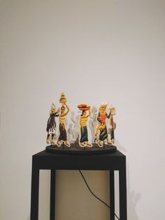 a group of figurines sitting on top of a black table next to a white wall