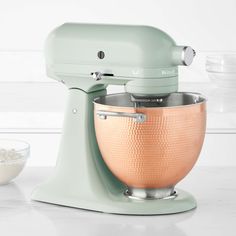 a green mixer sitting on top of a counter next to a bowl with white rice in it