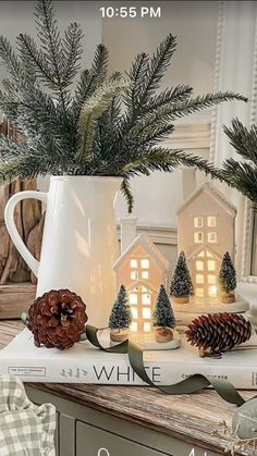 a white coffee cup filled with pine cones on top of a table next to christmas decorations