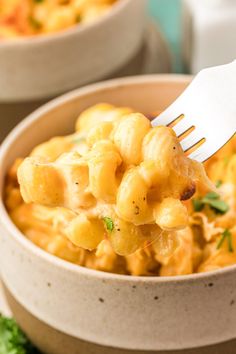 a fork full of macaroni and cheese in a bowl