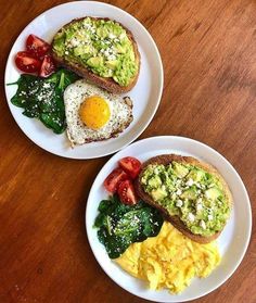 two white plates topped with eggs and vegetables on top of a wooden table next to each other