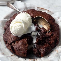 a chocolate cookie with ice cream on top and a spoon in the bowl next to it