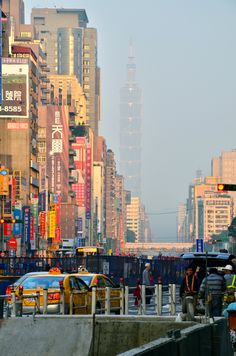 there are many people walking down the street in this city with tall buildings behind them