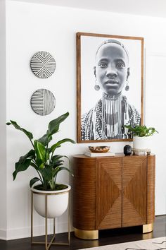 a living room with plants and pictures on the wall, including a plant in a pot