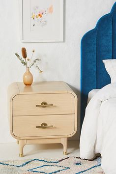 a blue headboard next to a white bed in a room with a painting on the wall