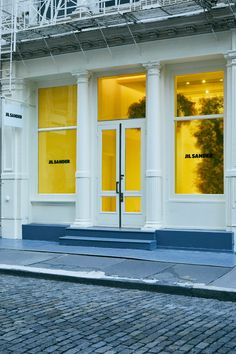 a building with yellow doors and windows on the side walk next to a brick sidewalk