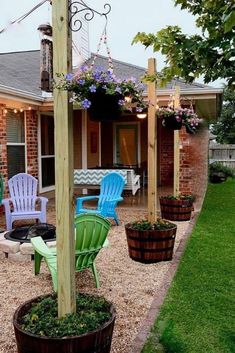 some chairs are sitting on the gravel in front of a house with flowers and lights