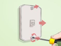 a hand holding a screwdriver near a light switch with arrows pointing towards it