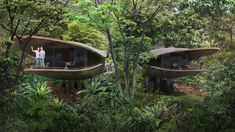 two people standing on the balcony of a house surrounded by trees