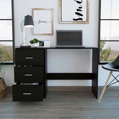 a black desk with a laptop on it in front of a window and a chair