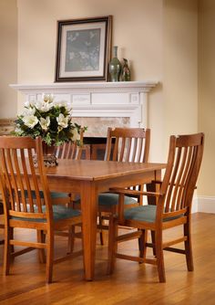 a wooden table with chairs around it in front of a fireplace