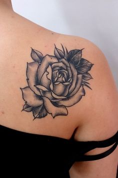 a black and white rose tattoo on the back of a woman's shoulder