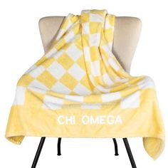 a yellow and white checkered blanket sitting on top of a chair next to a pillow