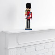 a toy soldier is standing on top of a mantel in front of a white brick wall