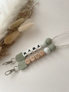 the name mama is spelled in small letters on keychains next to a feather