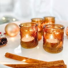 some candles are sitting on a plate next to christmas ornaments and pineconi cones