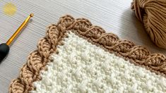 a crochet afghan with a ball of yarn next to it and a pair of scissors