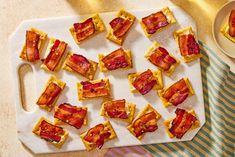 bacon and cheese bites on a cutting board next to a cup of tea or coffee