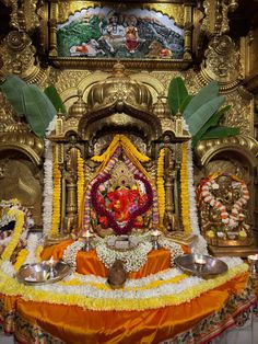 the altar is decorated with flowers, candles and an idol in front of a painting