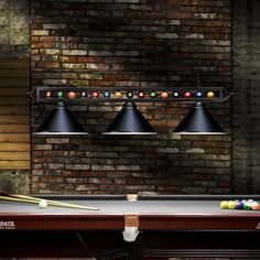 a pool table with two billiards and three lights hanging from the ceiling next to a brick wall