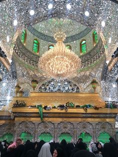 a group of people standing in front of a large chandelier inside of a building