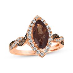 a brown and white diamond ring with an oval shaped stone surrounded by two smaller diamonds