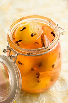 a glass jar filled with oranges sitting on top of a white table cloth next to a