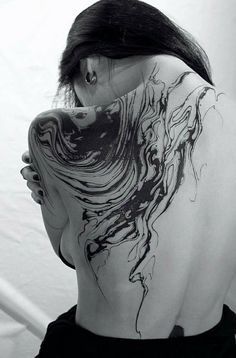 the back of a woman's neck with black and white ink art work on it