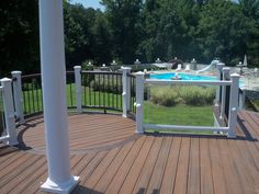 a wooden deck with an above ground pool and white pillars on the top of it