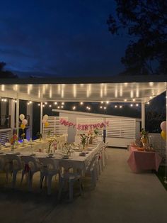 an outdoor birthday party setup with balloons and lights on the ceiling, tables set up outside