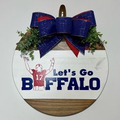 a wooden sign that says let's go buffalo on it with a bow hanging from the front