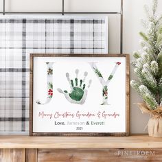 a christmas card with the word joy and handprint on it next to a potted plant