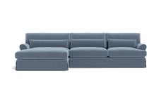 a blue sectional sofa with pillows on the top and bottom, sitting in front of a white background