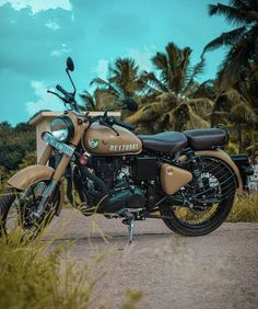 the motorcycle is parked on the side of the road near some grass and palm trees