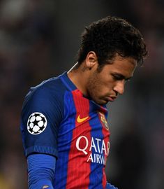 the soccer player is looking down at his ball while wearing blue and red jerseys