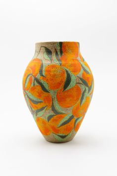 an orange and green vase sitting on top of a white table