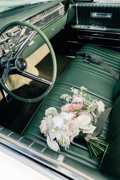 a bouquet of flowers is sitting on the seat of an old car with leather upholstered