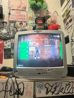 an old tv sitting on top of a table with graffiti all over the walls behind it