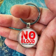 a person holding a keychain with the words no blood on it in red and white