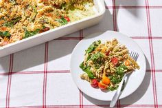 a white plate topped with pasta next to a casserole dish filled with vegetables