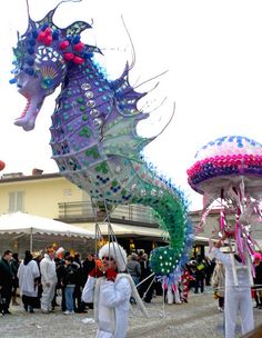 some people are walking around with kites in the shape of sea horses and jellyfish