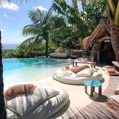 an outdoor swimming pool with chaise lounges next to it and palm trees in the background