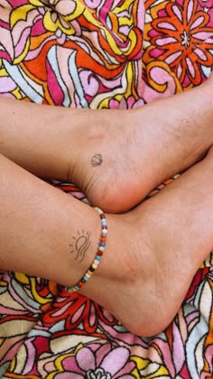 two people with tattoos on their legs and feet are laying on a colorful blanket together