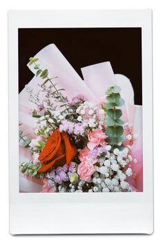 a bouquet of flowers is wrapped in pink and white paper, with greenery on top