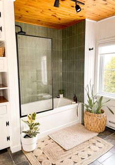 a bath room with a tub a rug and a window on the floor in front of it