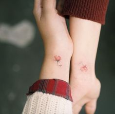 two people with matching tattoos on their arms, both holding each other's hands