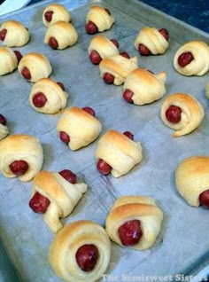 hotdogs wrapped in crescented bread on a baking sheet with ketchup