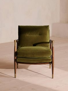 a green chair sitting on top of a hard wood floor next to a white wall