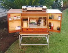 an old fashioned stove with its doors open on the grass in front of a house