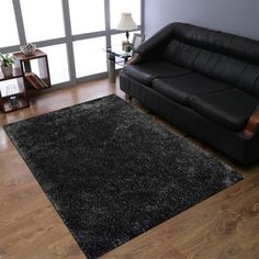 a living room with a black couch and wooden floors in front of a large window